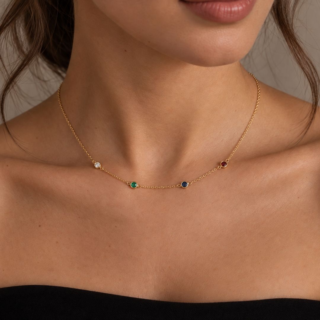 Woman wearing the gold Fable Necklace with four small birthstones spaced along the chain